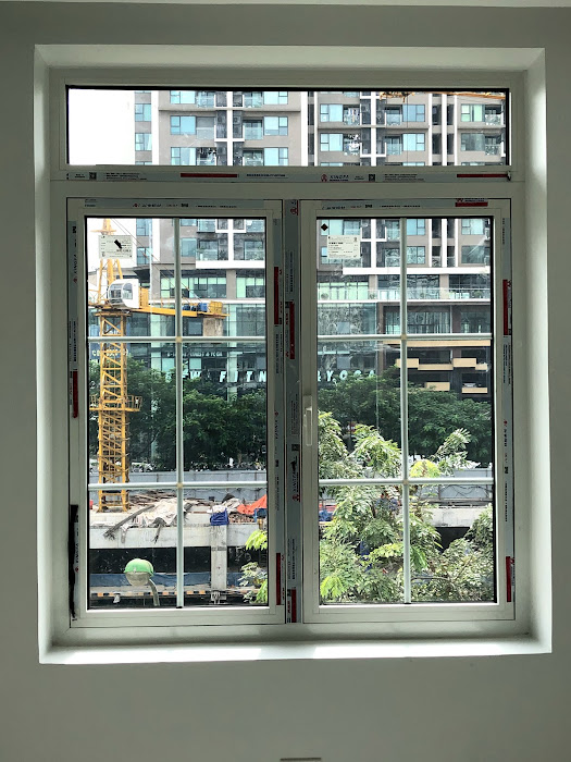 Cửa sổ nhôm kính hộp hai cánh mới lắp đặt nhìn ra công trình xây dựng và tòa nhà cao tầng